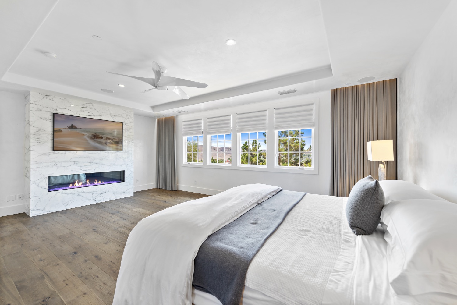 The same bedroom after renovation, with a linear fireplace and stone surround